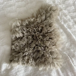 Beige oneshoulder topp med volanger från S.T.L - Säljer en beige oneshoulder topp från S.T.L med massor av volanger i mesh framtill. Toppen har en asymmetrisk form och är croppad, vilket ger en unik och trendig look. Perfekt för dig som vill sticka ut med coola detaljer och mjuka färgtoner. (Pris går att diskutera) 