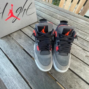 Nike Air Jordan 4 Retro grå/röd - Kan sänka pris.  Säljer ett par Nike Air Jordan 4 Retro i grå mocka med svarta och röda detaljer. Skorna har klassisk meshpanel, svart snörning.