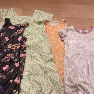 Fyra somriga klänningar från H&M & Wonder Nation - Säljer fyra klänningar i olika stilar: en svart med blommigt mönster, en ljusgrön med små blommor och volang, en gul med vita blommor från H&M och en vit spetsklänning med regnbågsrandig krage från Wonder Nation. Perfekt för dig som gillar färg och mönster! 4 riktigt somriga klänningar 👗 🤗