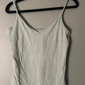 Ljusgrå linnetopp från 157 - Säljer en enkel och stilren ljusgrå linnetopp från 157 i storlek M. Toppen har smala axelband och en mjuk v-ringad halsringning. Materialet är 95% bomull och 5% elastan vilket gör den skön och stretchig. Perfekt att matcha med jeans eller shorts.
