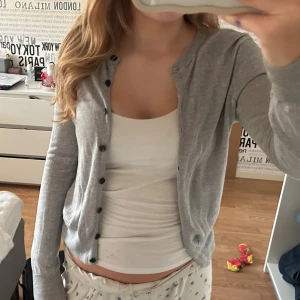 Grå kofta från Zara, storlek S💕 - Snygg grå kofta från Zara i storlek S. Koftan har rund hals, svarta knappar framtill och är långärmad med ribbade muddar. Materialet är mjukt och känns som bomull