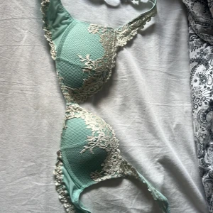 Mintgrön spetsdetaljerad bh-topp - Snygg mintgrön bh-topp med vackra spetsdetaljer i beige längs kanterna. Kuporna är lätt vadderade och har en diskret struktur. Axelbanden är justerbara och toppen har en feminin och elegant look.