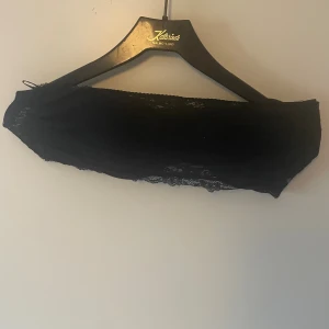 BH - Säljer en svart bandeau BH från Body Secrets i storlek 80B. Toppen är gjord i spets med fina detaljer och är axelbandslös, perfekt för att ge en snygg och stilren look.
