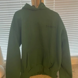 Grön hoodie från Dropsize storlek S - Säljer en grön hoodie från Dropsize med broderad logga på bröstet. Tröjan har huva, stor magficka och ribbade muddar vid ärmslut och nederkant. Helt ny aldrig använd, storlek S.