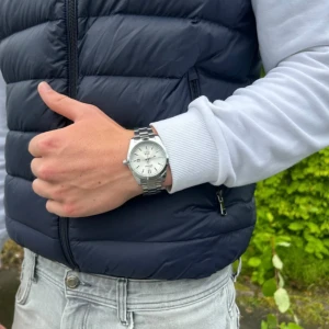 Silverfärgad  herrklocka från Doventi  - Säljer en stilren från Doventi herrklocka i silver med rund boett och länkarmband i metall. Urtavlan är vit med tydliga index och datumvisning. Perfekt för dig som gillar klassisk design och vill ha en klocka som syns på handleden.