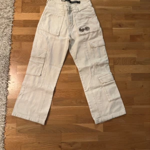 Vita cargopants från Lost Boys och vicinity - Säljer ett par vita cargopants från Lost Boys x Vicinity i storlek S. Byxorna har flera stora fickor på benen och bak, samt en cool patch på framsidan. De är raka i modellen och har en loose passform. Materialet är robust bomull som ger en skön känsla.