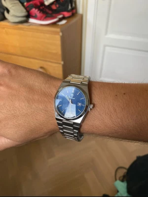 herrklocka 41mm blå urtavla rostfritt stål - Snygg herrklocka med blå urtavla och subtilt rutmönster. Klockan har en rund form, datumvisning och silverfärgat armband i metall. Perfekt accessoar för dig som gillar klassisk design.