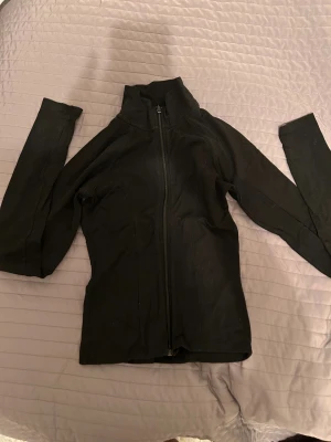 Svart vindjacka från Gina Tricot XS - Svart vindjacka från Gina Tricot i storlek XS. Jackan har en hög krage, hel dragkedja framtill och långärmade smala ärmar. Materialet är mjukt och lätt, perfekt för svala dagar. Enkel och stilren design som funkar till många outfits.