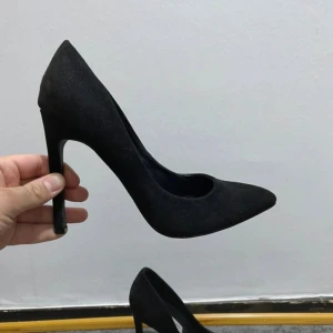 Svarta pumps med spetsig tå från Boohoo - Säljer ett par klassiska svarta med hög klack och spetsig tå. Skorna är i mocka-look och har en elegant siluett som ger en snygg och stilren vibe. Perfekta för dig som gillar en tidlös och chic stil.