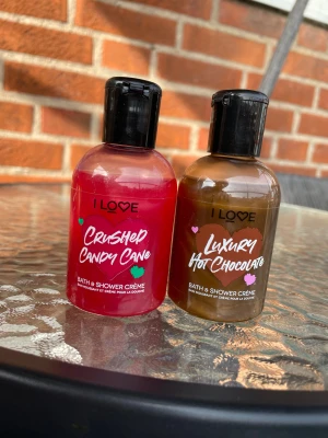 I Love Bath & Shower Crème duo. Crushed candy cane och Luxury hot chocolate - Två flaskor duschkräm från I Love i dofterna Crushed Candy Cane (röd) och Luxury Hot Chocolate (brun). Varje flaska rymmer 100 ml och har svart snäpplock. Perfekt för dig som älskar söta och chokladiga dofter i duschen.