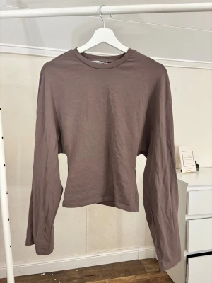 Brun långärmad topp i bomull - En enkel och stilren brun långärmad topp i mjuk bomull. Modellen har rund halsringning och en rak passform som passar till det mesta. Perfekt för dig som gillar en clean och avslappnad look.