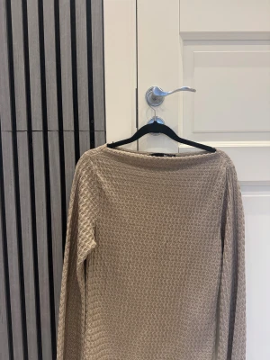 Beige långärmad tröja  - Beige långärmad tröja med vågigt mönster och bred halsringning och dessutom så är materialet är mjukt och skön.