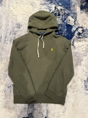 Grön Ralph Lauren hoodie -  Säljer en snygg olivgrön Rayen hoodie. Äkta, som man kan se på bild 6. Inga defekter alls! Dunder skick. Storlek M, kan även passa S. Han på bild är 185 cm, 75 kg. Hör av er vid funderingar!