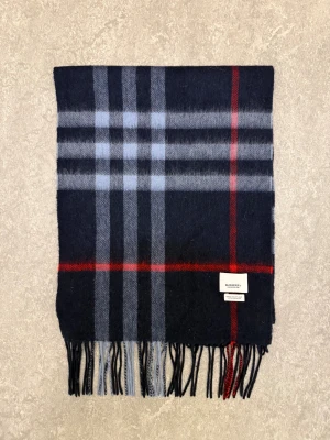 Burberry Halsduk - Tja! Säljer denna stilrena blårutiga burberry halsduken. Använt ett bra tag, fick den av min farsa och han köpte den i London. Nypris ca 4600kr. Finns inga defekter och den är i jättebra skick! Priset är ej hugget i sten! Tveka inte att kontakta vid frågor eller funderingar!