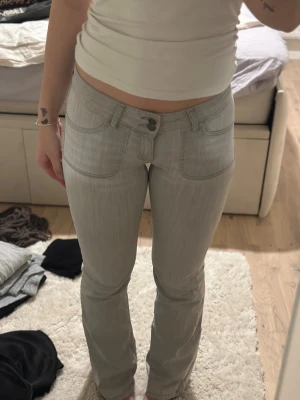Ljusgrå bootcut jeans  - Säljer ett par ljusgrå jeans med bootcut-modell från Nelly. De har snygga fickdetaljer både fram och bak. Byxorna har låg midja och är utsvänga. 💘