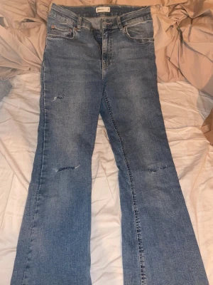 Blå jeans med slitningar - Snygga blå jeans från Gina tricot  Jeans med klassisk femficksdesign och raka ben. Jeansen har coola slitningar på båda benen och är tillverkade i mjukt denimtyg. Passar dig som gillar en avslappnad och trendig look.