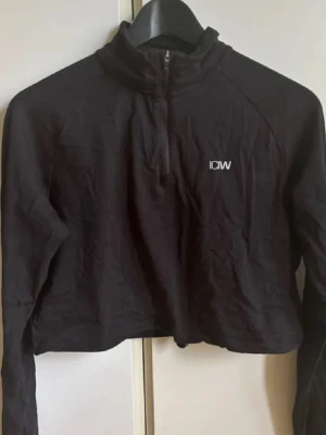 Svart cropped tröja från ICIW - Svart cropped långärmad tröja från ICIW med half zip framtill och den är helt ny med prislapp