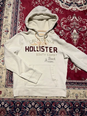 Vintage Hollister hoodie - Säljer nu en av dessa sällsynta och eftertraktade Hollister hoodies. Vit färg och coolt tryck på framsidan. Bra skick, en missfärgning på baksidan av ena ärmen(se bild 3), men den går nog att få bort. Storlek M. Hör av er vid funderingar 🙌
