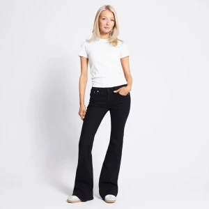 Svarta bootcut jeans med hög midja - Snygga svarta jeans med bootcut-snitt och hög midja. Byxorna har klassisk femficksdesign och är tillverkade i stretchigt jeansmaterial som sitter bekvämt. Perfekt för dig som gillar en retro och trendig look med utsvängda ben.