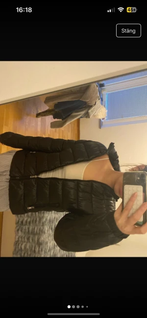 Svart pufferjacka med dragkedja - Säljer en svart pufferjacka med hög krage och två praktiska fickor med dragkedja. Jackan är quiltad och har en stilren look som passar perfekt till kalla dagar. Långärmad och med en snygg, normal passform. Perfekt för dig som vill ha en enkel men trendig jacka.