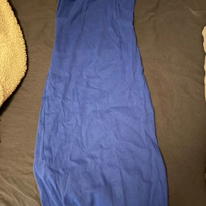 Marinblå långklänning i ribbad bomull - En stilren marinblå långklänning i ribbad bomull. Klänningen har en enkel och smickrande passform som följer kroppen. Perfekt för dig som gillar minimalistisk stil och vill ha något bekvämt men ändå snyggt.