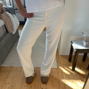 Vita linnebyxor med rak passform - Snygga vita linnebyxor med rak passform och klassisk midja. Byxorna har en enkel design utan synliga detaljer och är perfekta för en avslappnad och stilren look. Lätta och luftiga, perfekta för varmare dagar.