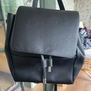 Svart ryggsäck i skinmaterial  - En svart väska av skinmaterial💓. Har knappt använt den då den är i bra skick💓.