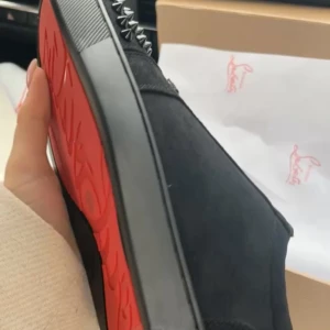Christian Louboutin sneakers med nitar - Säljer ett par svarta sneakers från Christian Louboutin med ikonisk röd sula och coola silverfärgade nitar på ovandelen. Skorna är i mocka och har en chunky svart sula som ger en edgy vibe. Perfekta för dig som vill sticka ut med lyxig streetstyle.