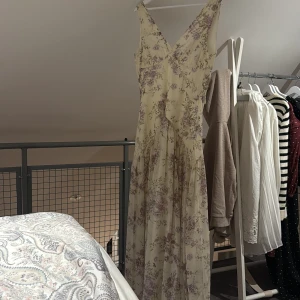 Lång blommig klänning Adoore - Helt ny långklänning från Adoore med lila blommönster. Klänningen är i nyskick med lapp kvar endast testad.  storlek 40.