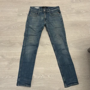 Replay Anbass blå jeans herr 29 - Snygga blå Replay Anbass jeans i klassisk femficksmodell. Jeansen har en rak passform med något smalare ben, normal midja och diskreta slitningar för en cool look. Tillverkade i mjukt denimtyg med Replay-logga på fickan.