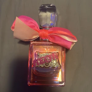 Juicy Couture parfym med rosett - Färgglad parfymflaska från Juicy Couture med en stor rosa rosett och dekorativ detalj framtill. Perfekt för dig som gillar lekfull och trendig stil. Volym och ingredienser syns ej på bilderna.