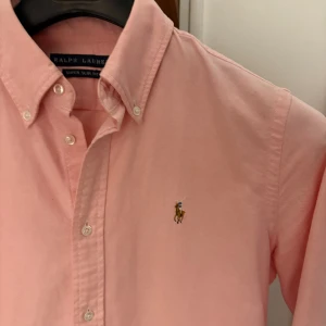 Ralph luren skjorta  - En snygg ralph lauren skjorta i färgen rosa. Knappt använd och är i riktigt bra stick. storlek 10 skulle säga sitter som s. Modell super slim. 