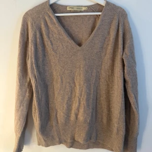 InWear stickad tröja  - Elegant beige tröja med V-ringning och långa ärmar. Tröjan har en ribbstickad detalj nedtill och vid ärmsluten. Passar perfekt för både vardag och fest. Storlek L/XL. Kaschmir. Fint skick men lite nopprig, se bild 2 och 4. 