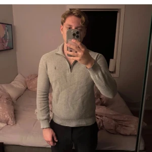 Grå half zip tröja Polo Ralph Lauren - Snygg grå tröja från Polo Ralph Lauren i pima bomull. Klassisk half zip med liten broderad logga på bröstet. Långärmad modell med ribbade muddar och krage. Perfekt för lager-på-lager och chill stil. Lagat ett hål på armen