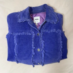 Lila manchesterjacka från Moschino - Snygg lila manchesterjacka från Moschino i storlek S. Använd endast 1 gång. Perfekt statement-plagg för dig som vill sticka ut.