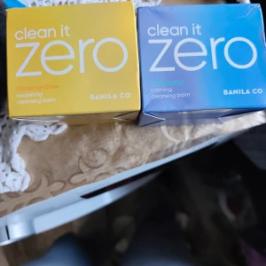 Banila Co Clean It Zero Cleansing Balm - Två olika Clean It Zero cleansing balms från Banila Co: Ginseng-Glow i gul förpackning och Cica-Relief i blå förpackning. Båda är rengöringsbalms som smälter bort smink och lämnar huden mjuk. Perfekt för att ta bort makeup och ge huden glow eller lugn.