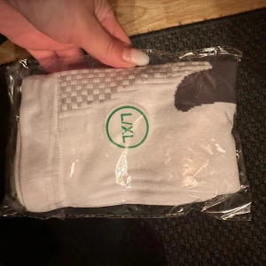 Vita och grå träningsstrumpor L/XL stödstrumpor - vita och grå strumpor i storlek L/XL, perfekta för träning. Strumporna har ett rutigt mönster upptill och är tillverkade i mjukt och slitstarkt material, troligen bomull och polyester. Snygg design med kontrastfärg vid häl och tå.Dessa strumpor erbjuder överlägsen komfort och stöd. Tillverkade av högkvalitativt, fukttransporterande tyg håller de dina fötter torra och svala. Kompressionstekniken ger optimalt stöd för att förbättra blodcirkulationen, minska muskeltrötthet och förebygga skador.