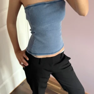 Blå ribbad bandeau tubtopp - Säljer en blå ribbad bandeau tubtopp med smala vita ränder. Toppen är tight och ärmlös, perfekt för varma dagar. Materialet känns mjukt och stretchigt, vilket gör den superbekväm att bära. Enkel och stilren design som passar till mycket.