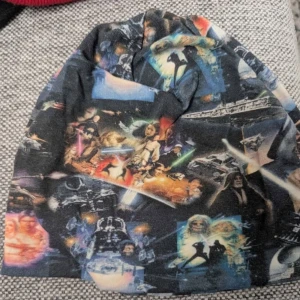 Star Wars mössa med tryck 8-12 år ca 56 - Cool mössa med färgstarkt Star Wars-tryck över hela ytan. Mjukt och stretchigt material som sitter skönt på huvudet. Perfekt för dig som älskar sci-fi och vill sticka ut med en unik accessoar.