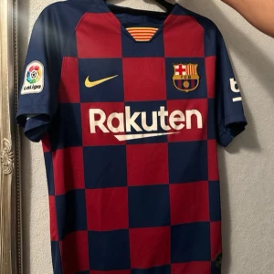 Barcelona Dri-Fit matchtröja Nike S - Säljer en officiell FC Barcelona matchtröja från Nike i storlek S. Tröjan har klassiskt rutigt mönster i mörkblått och rött, med korta ärmar och Dri-Fit material som andas. Tryck med Rakuten och UNICEF samt La Liga-märke på ärmen. Perfekt för dig som älskar Barca!