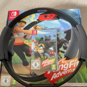 Nintendo Switch Ring Fit Adventure - Komplett Nintendo Switch Ring Fit Adventure med original ring, benrem och spelkassett. Allt i fint skick, redo för träning och spel. Perfekt för dig som vill kombinera motion och underhållning hemma.
