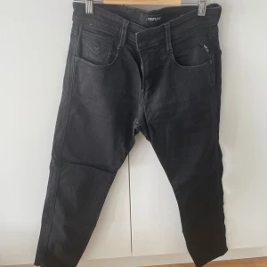 Svarta Replay jeans i slim fit - Svarta jeans från Replay med klassisk femficksdesign och smal passform. Jeansen har en snygg, enkel look och är tillverkade i stretchigt bomullsmaterial för extra komfort. Perfekta för dig som gillar stilrena och moderna byxor.