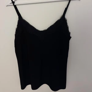 Svart linnetopp med spets - snygg linnetopp i svart med tunna axelband och spetsdetaljer längs v-ringningen. Perfekta för lager-på-lager eller att bära som de är. Toppens material känns mjukt och följsamt mot huden. det blå linnet är samma linne bara i annan färg men visar hur det sitter