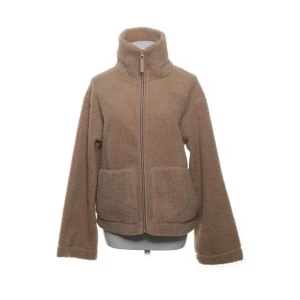 Beige teddyjacka från H&M - Mysig beige teddyjacka från H&M med hög krage och dragkedja framtill. Jackan har två stora fickor och är tillverkad i 100% polyester. Perfekt för kyliga dagar och ger en chill vibe till din outfit.