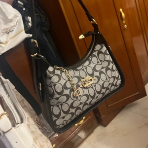 Coach axelväska med monogram och kedja - Snygg fejk Coach väska med klassiskt monogrammönster i svart och grått. Inte använd i nytt skick.