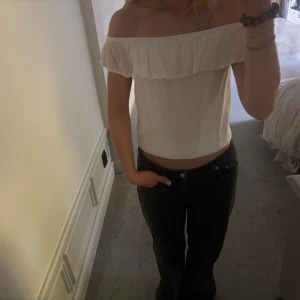 Vit offshoulder topp med volang - Snygg vit offshoulder topp med bred volang runt hela axelpartiet. Enkel och stilren design som passar till många olika outfits.