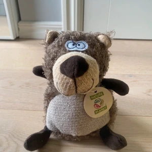 Fancy Bear - Fancy Bear från Nature Planet är ett mjukt och charmigt gosedjur med lockig päls och broderade detaljer. Märkt med originaltagg, tillverkad av återvunna material och tryckt med sojabläck. Skicket är mycket gott, inga synliga defekter eller slitage. Perfekt som present eller samlarobjekt.