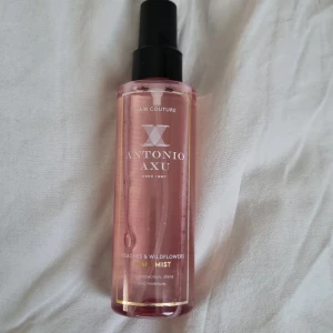 Antonio Axu Peaches & Wildflowers hair Mist - Fräsch face mist från Antonio Axu med doft av persika och vilda blommor. Kommer i en rosa plastflaska med svart spraymunstycke. Ger UV-skydd, glans och fukt till håret. Innehåller 150 ml och är tillverkad i Sverige. Ej använd.