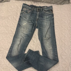 Blå Replay jeans med slitningar - Säljer ett par blå Replay jeans med snygga slitningar, ⚠️obs jeansen är väldigt slitna och sköra, ställ frågor innan köp⚠️. Jeansen har klassisk femficksdesign, slim passform. Färgen är mellanblå med ljusare tvättade partier och detaljerade sömmar på bakfickorna.