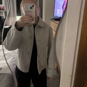 Grå kappa strl XS - Säljer en stilren grå jacka från 157 i storlek XS. Jackan har klassisk krage, stora framfickor och knäppning med stora knappar. Perfekt för dig som gillar minimalistisk och clean stil. Super skön kappa, passar perfekt nu till hösten 💕Pris och fler bilder kan diskuteras💕